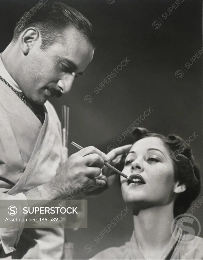 Male make-up artist applying a model's lipstick