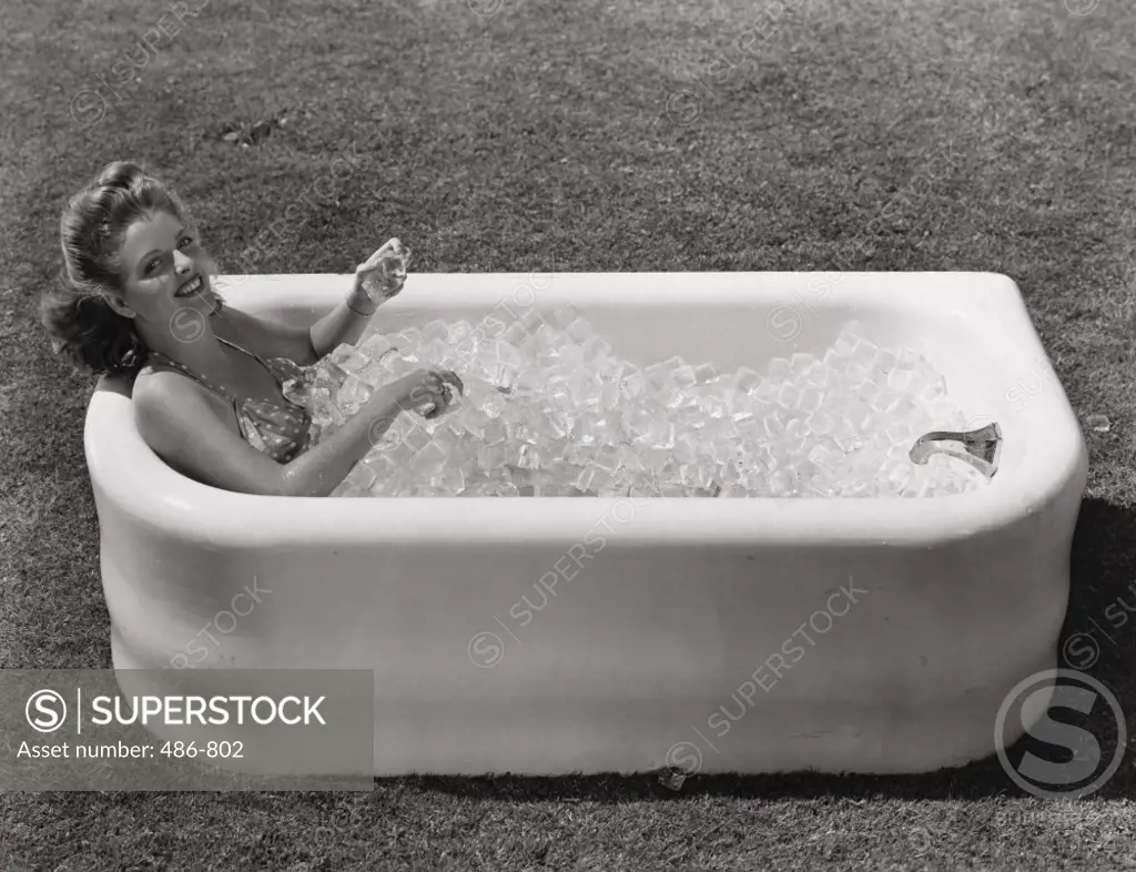 High angle view of a young woman in a bathtub with ice cubes