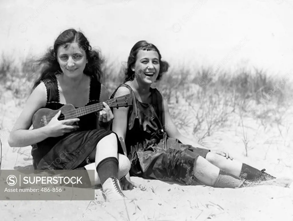 Two young women in swimwear relaxing on beach