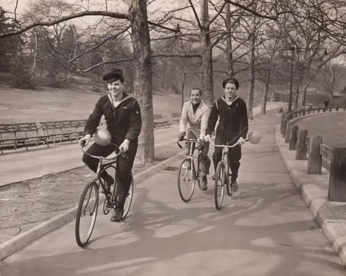 Three men riding bicycles