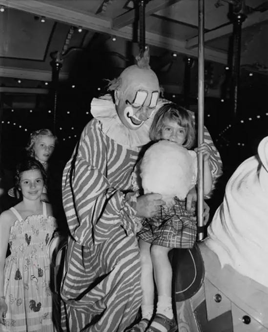 Clarabel, Tv's ""howdy doody"" clown, treating girl to wad of cotton candy on carouse at Patisades Park, 1951
