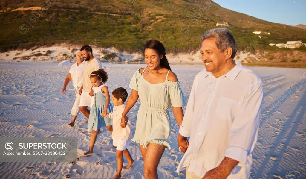 Multi generation family holding hands and walking along the beach together. Mixed race family with two children, two parents and grandparents enjoying summer vacation