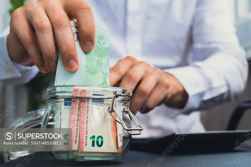 Man hands counting expenses banknotes of euro cash from glass jar in the piggy bank on calculator. Close up of hands unrecognizable Businessman. Save up budget investment concept. Euros fund savings