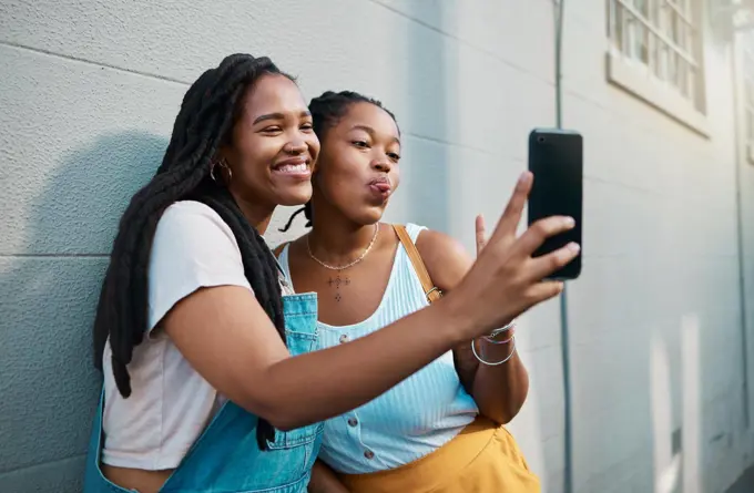 Black women, friends and phone selfie in city, street or outdoor. Relax, bonding and African girls spending quality time together, comic face and sharing picture post on social media with 5g mobile.