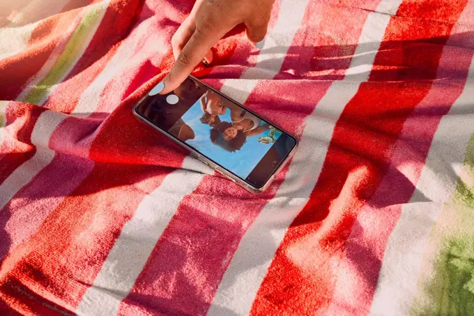 Hand, phone and selfie by friends at a beach for travel, fun and picture on towel, finger and screen. Women, hands and social media influencer set timer for recording, content creator and smartphone