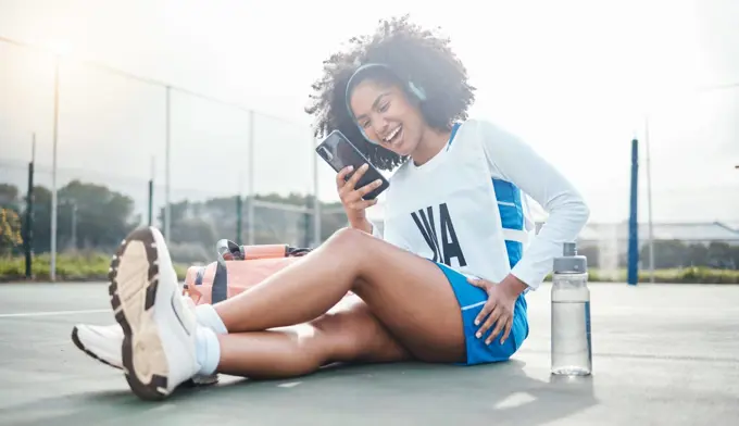 Netball sports, smartphone music and black woman listening to mp3 radio, audio podcast or media song. Laughing, online digital headphones and athlete streaming funny meme video after training workout