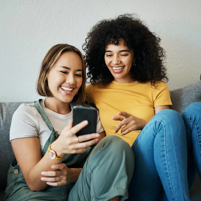 Friends, relax on sofa with smartphone and chat online with communication, funny meme and reading text message. Women with technology, mobile app and typing on social media with connectivity at home
