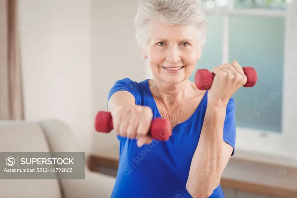 Portrait of senior woman exercising with dumbbells at home