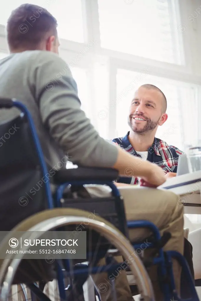 Low angle view of handicap businessman sitting with colleague in creative office