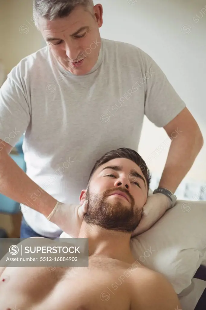 Physiotherapist examining neck of a patient in clinic