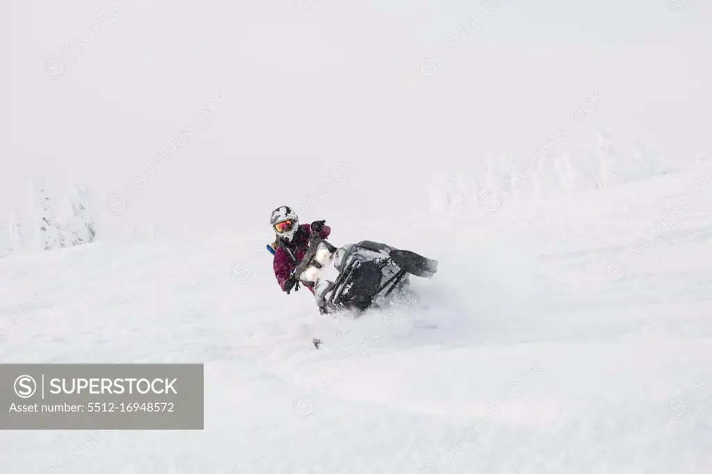Woman riding snowmobile in snowy alps during winter