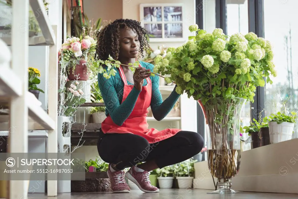 Female florist arranging flowers on flowerpot in flower shop