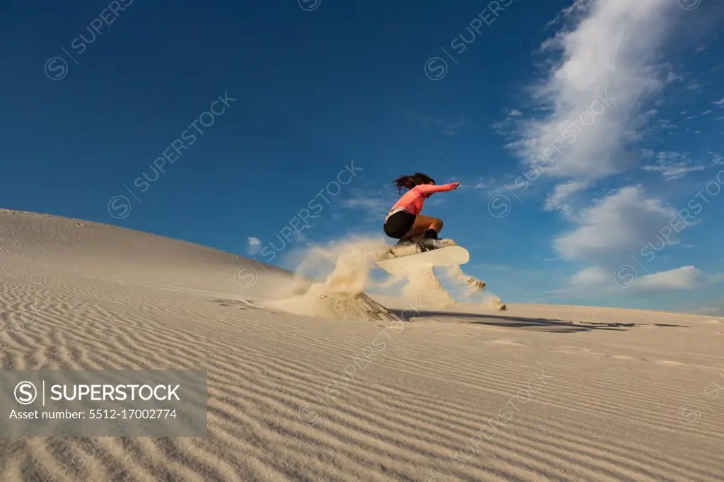 Woman sandboarding on sand dune at desert