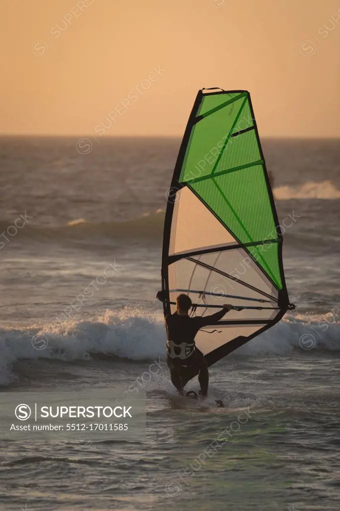 Male surfer surfing with surfboard and kite at beach