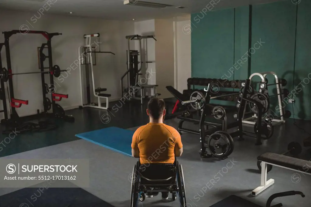 Rear view of handicapped man relaxing on wheelchair in gym