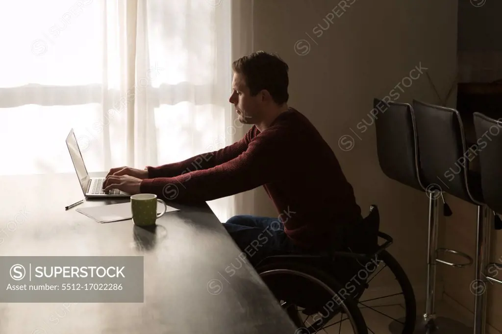 Disabled man using laptop on dinning table at home