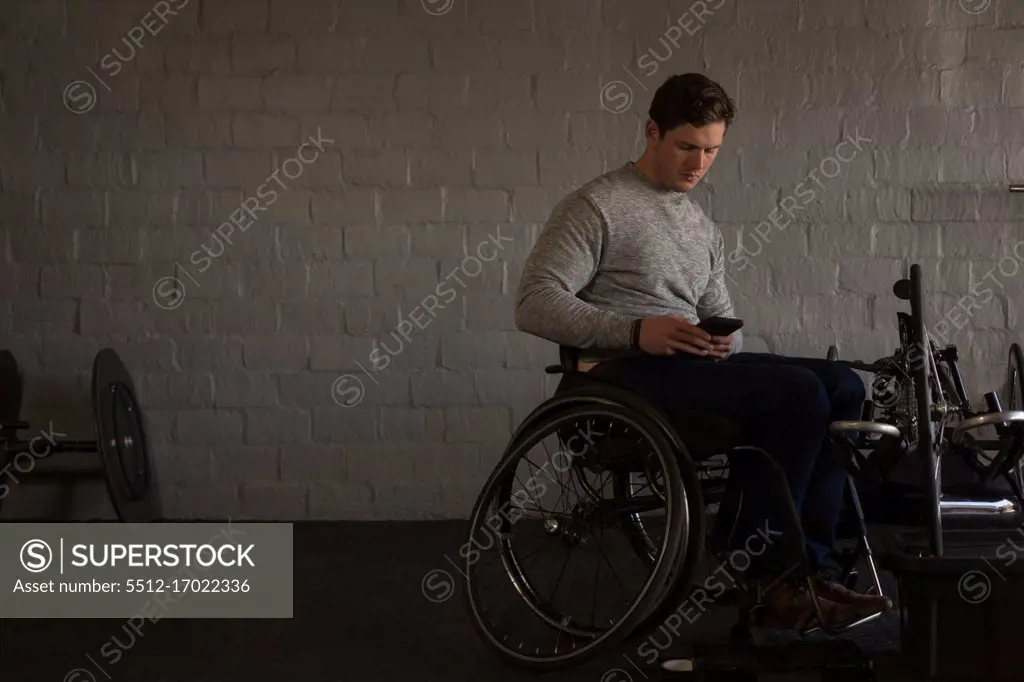 Young disabled man using mobile phone in workshop