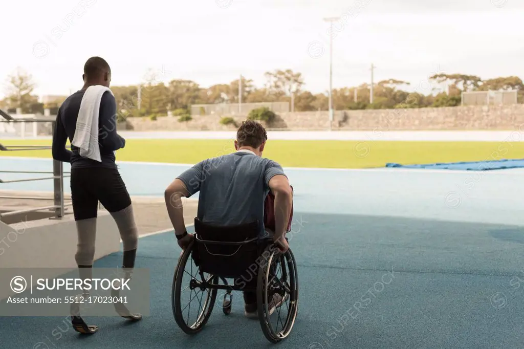 Rear view of two disabled athletics walking together on sports venue