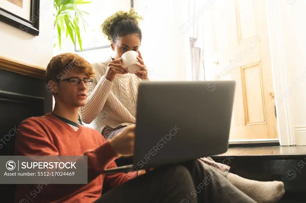 Couple having coffee while using laptop at home