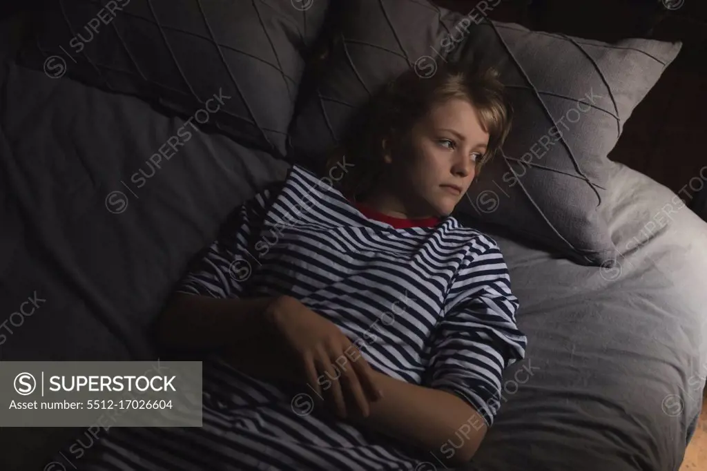 Thoughtful woman relaxing on bed in bedroom