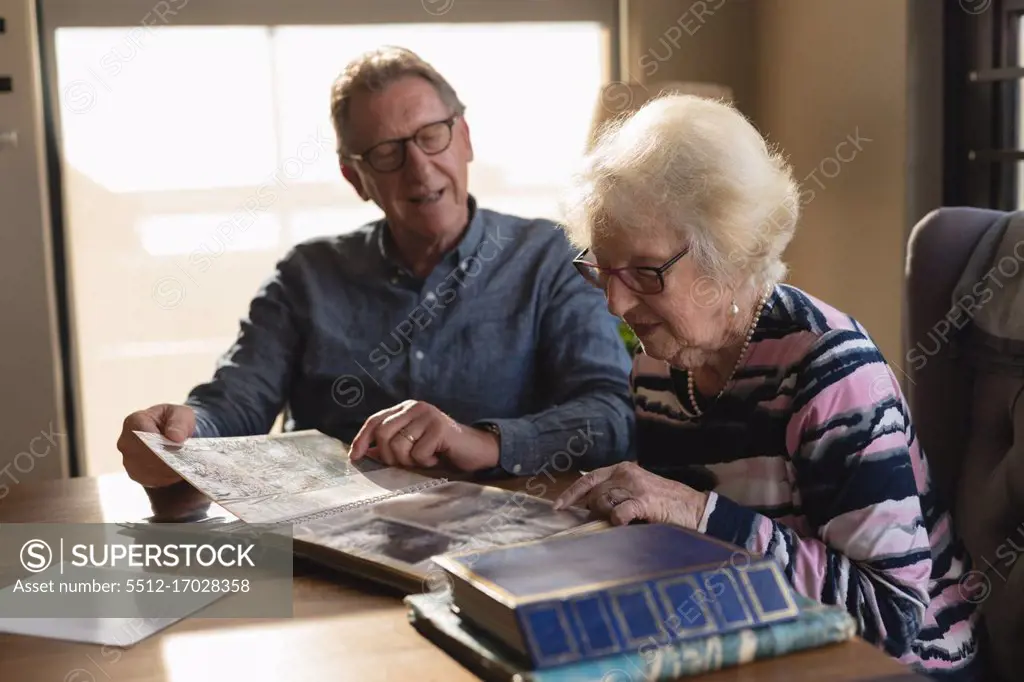 Senior couple looking photo album in living room at home