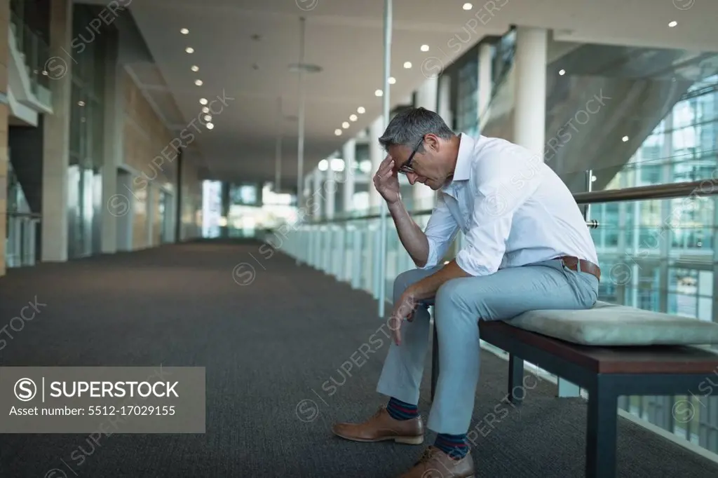 Side view of frustrated businessman sitting on the bench in office