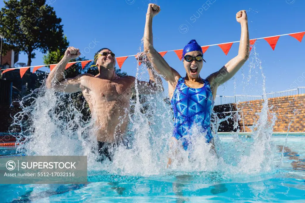 Front view of excited male and female swimmers celebrating their victory in the swimming pool on a sunny day