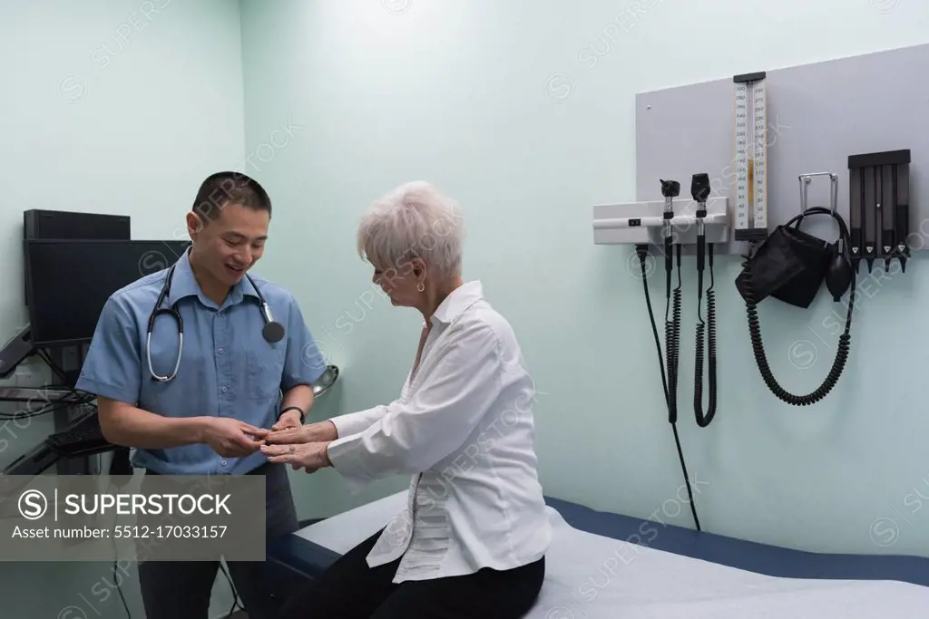 Young Asian male doctor examining a senior patient in the clinic while touching her hands