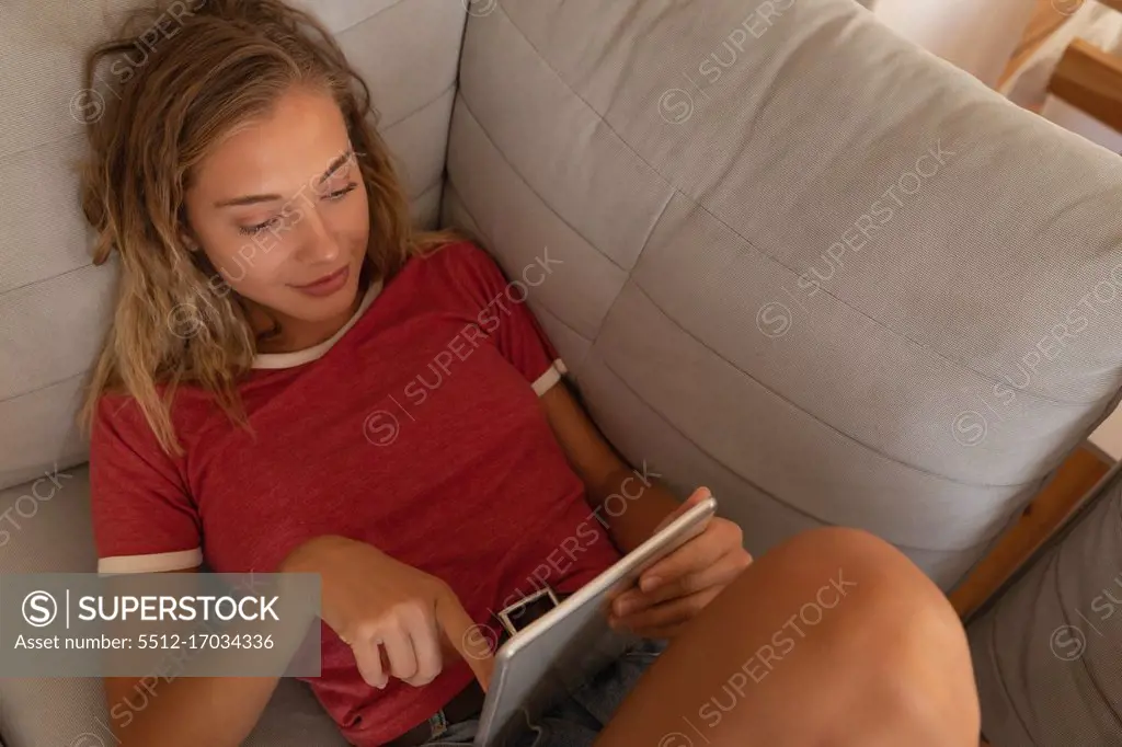 High angle view of caucasian woman using digital tablet in living room in sofa at home 