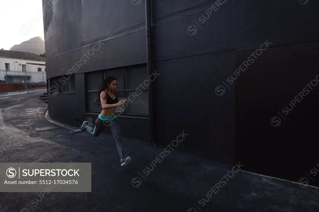 Side view of a young fit mixed-race girl running in the street