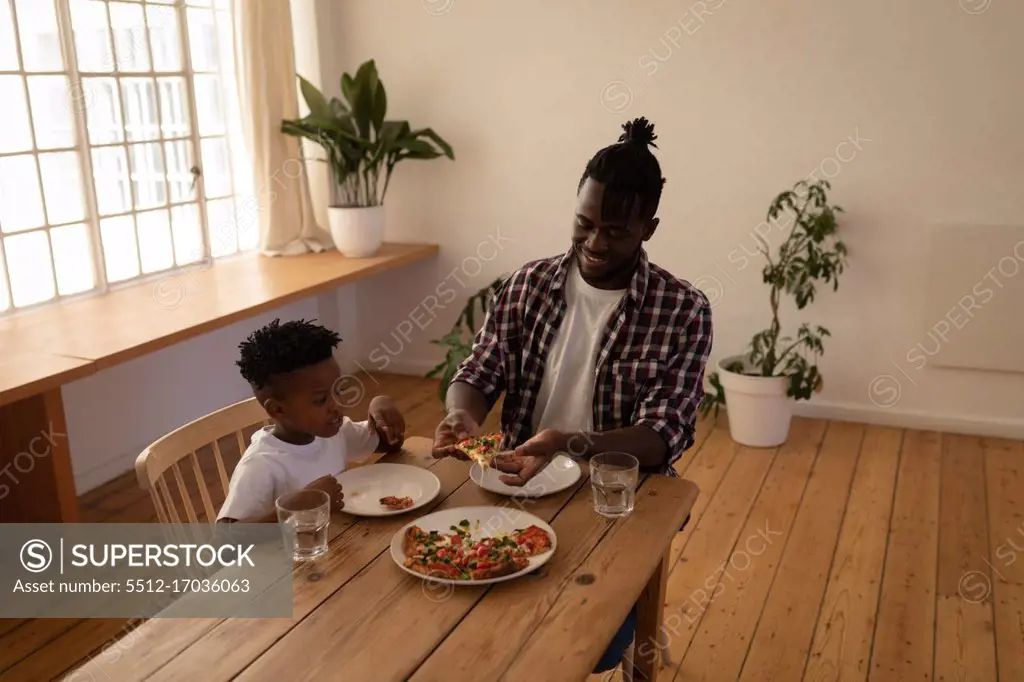 Front view of father and son having pizza at home
