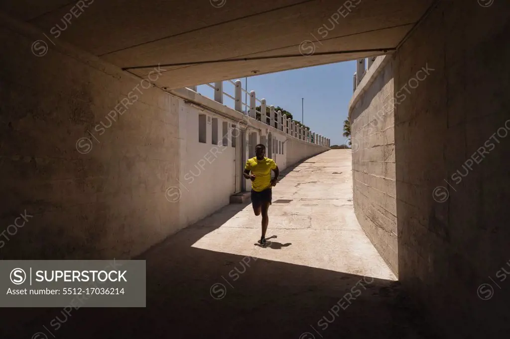 Front view of man running under the bridge on a sunny day