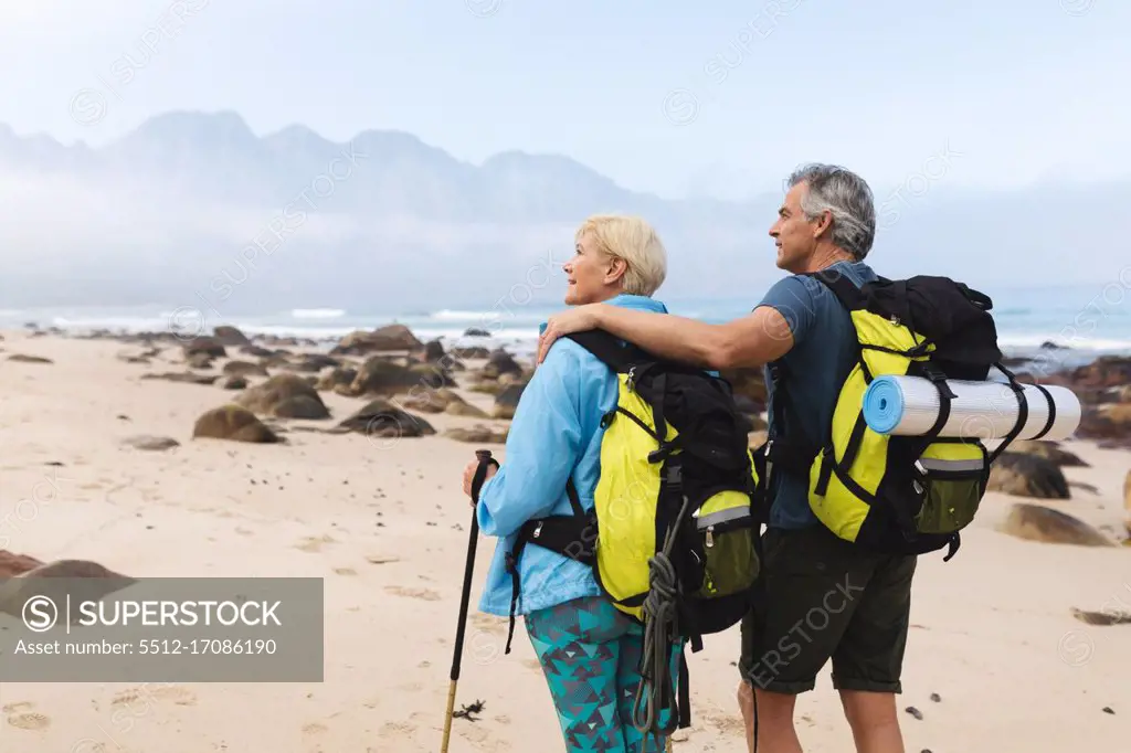 Senior couple spending time in nature together, walking on the beach, man is embracing woman. healthy lifestyle retirement activity.
