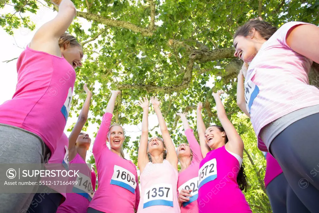 Smiling women running for breast cancer awareness on a sunny day