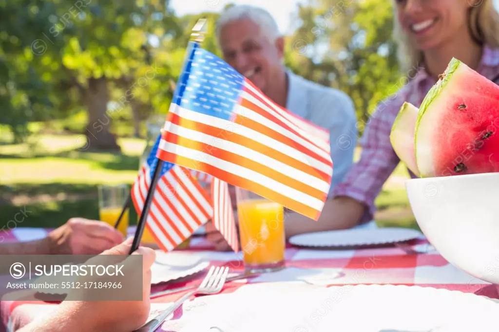 Happy family having picnic and holding american flag on a sunny day