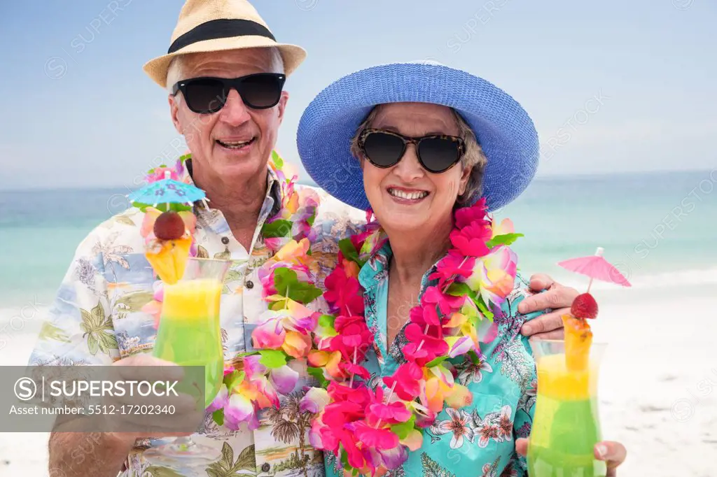 Happy senior couple with a cocktail drink on beach