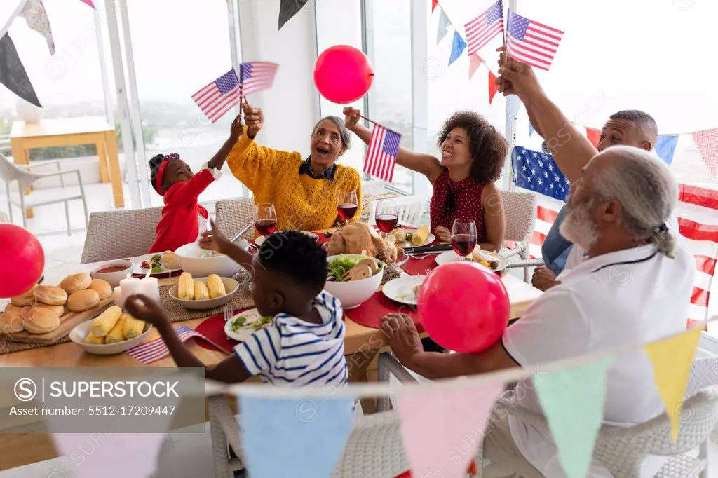 Side view of Multi-generation African American family celebrating US Independence day on a dining table at home