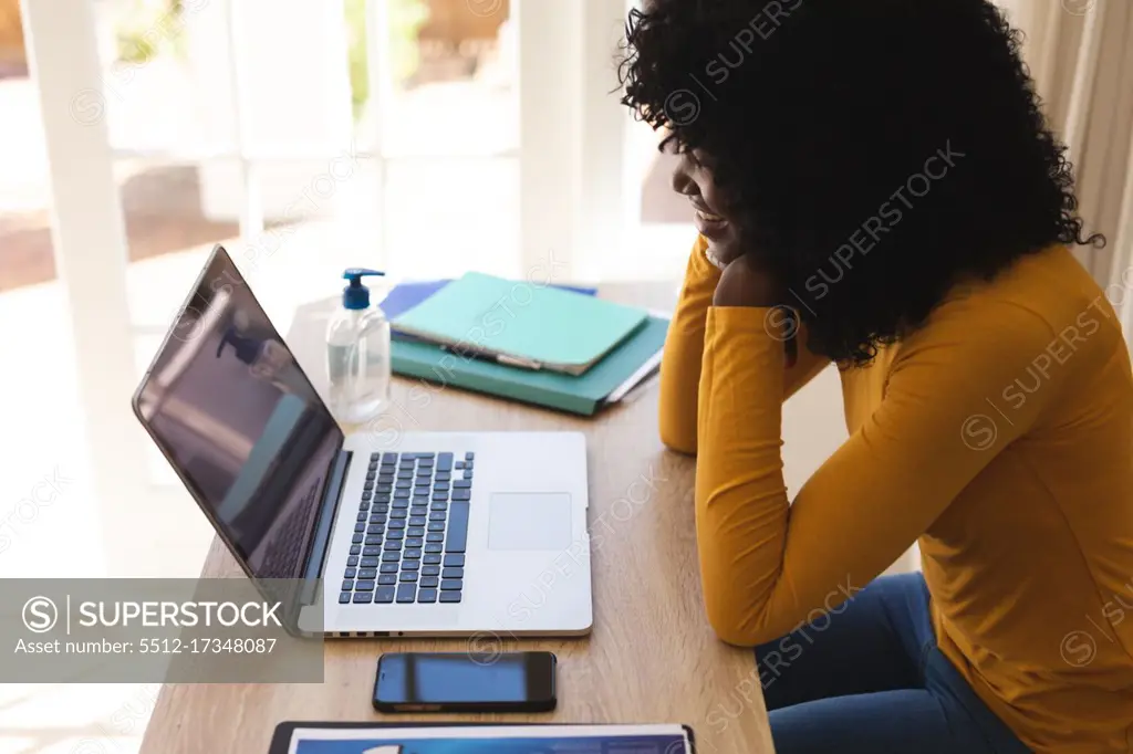African american woman having a video chat on laptop while working from home. social distancing during covid 19 coronavirus quarantine lockdown.