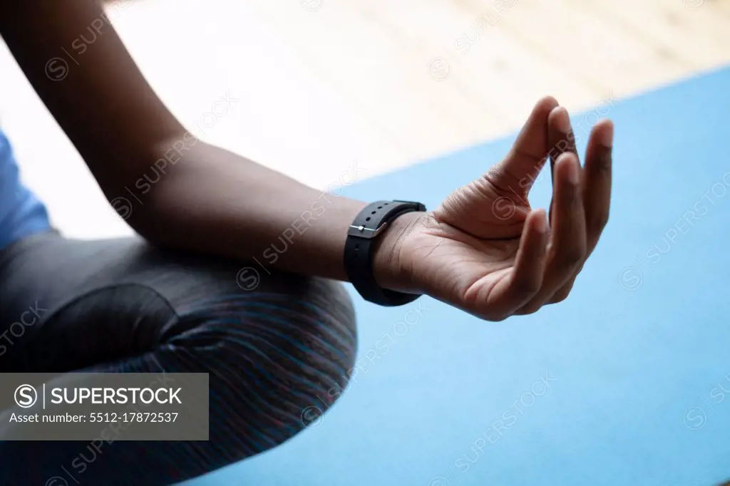 Close up of african american woman practicing yoga at home. staying at home in self isolation in quarantine lockdown