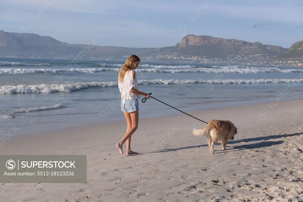 Caucasian woman walking a dog at the beach. healthy outdoor leisure time by the sea.