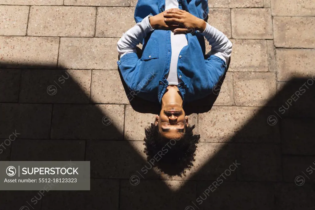 Mixed race male with moustache lying on street with eyes closed and relaxing. green urban lifestyle, out and about in the city.