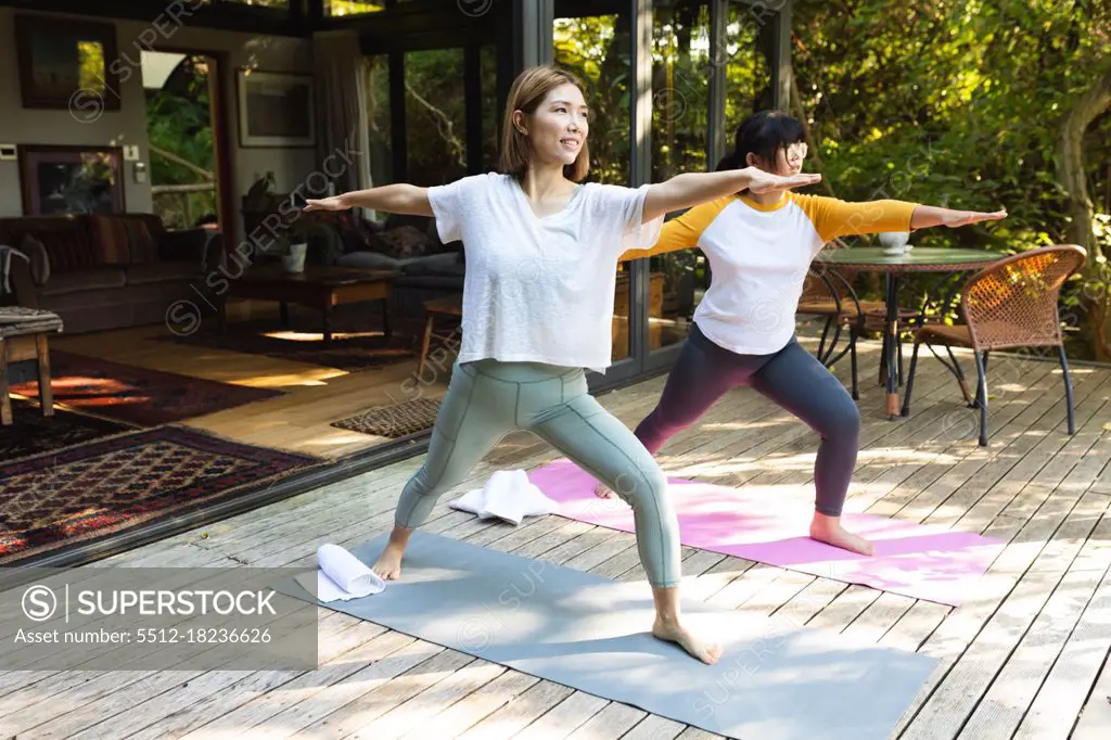 Asian mother and her daughter practicing yoga on terrace in garden. at home in isolation during quarantine lockdown.