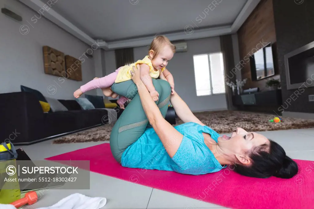 Caucasian mother holding her baby and doing yoga at home. motherhood, love and baby care concept