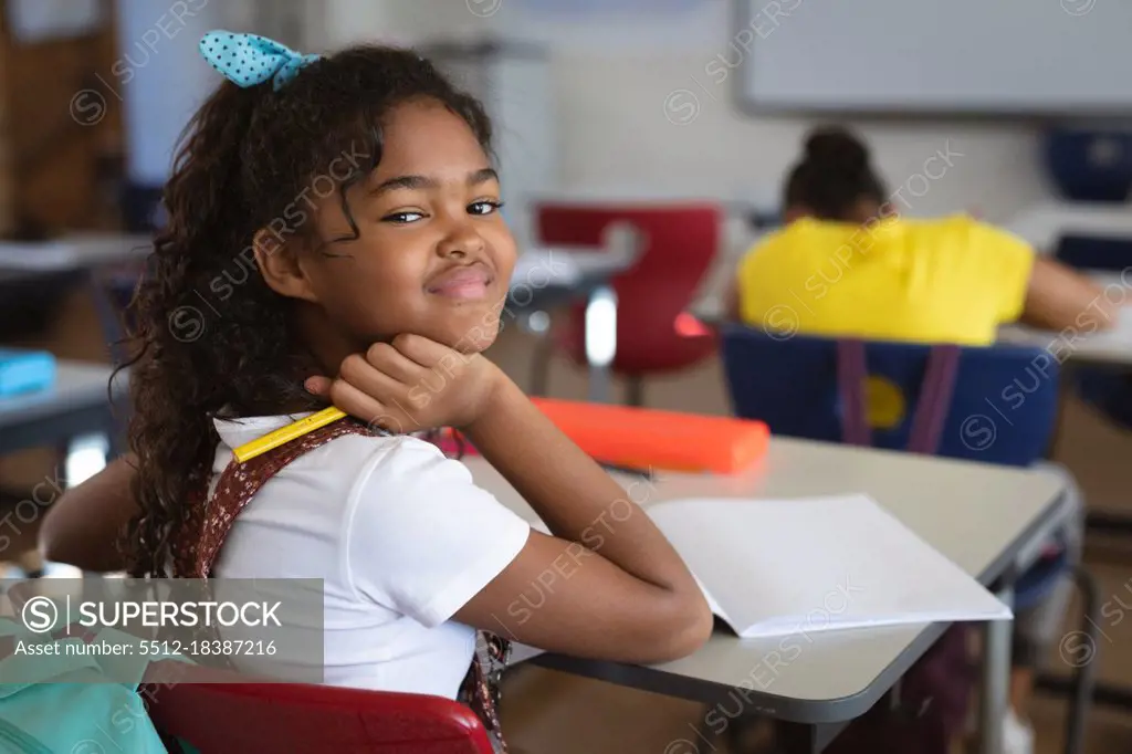 Portrait of african american girl sitting on her desk in the class at school. school and education concept