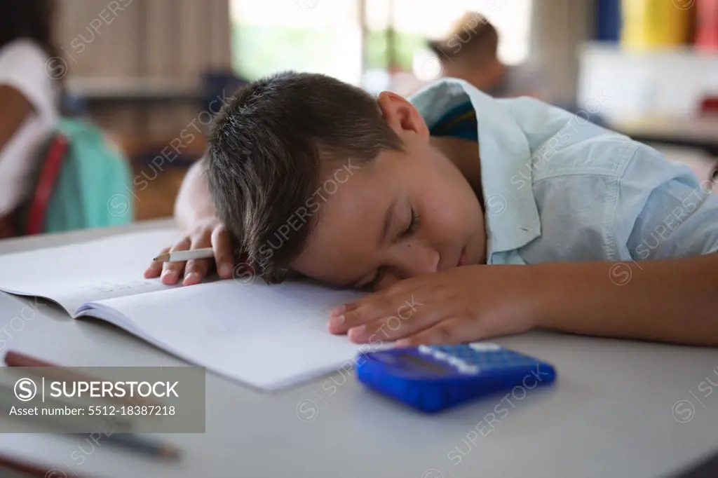 Caucasian boy sleeping on his desk in the class at school. school and education concept