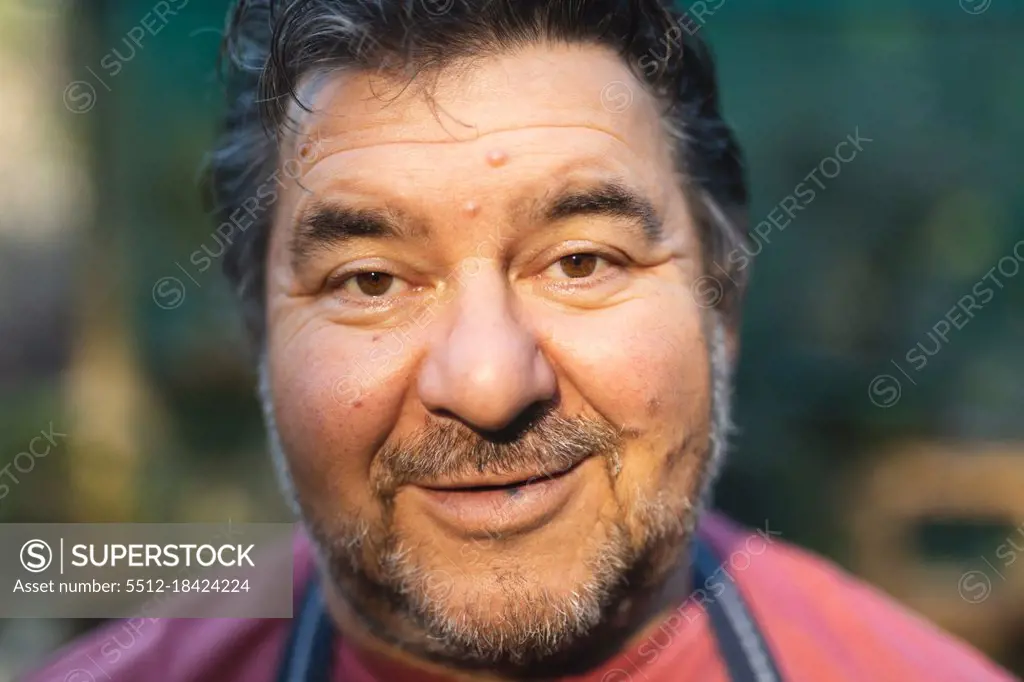 Portrait of happy caucasian male gardener looking at camera at garden centre. specialist working at bonsai plant nursery, independent horticulture business.