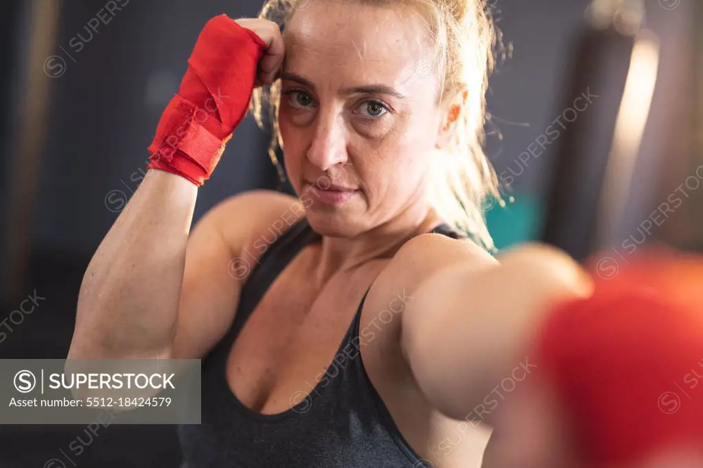 Portrait of caucasian woman exercising at gym, looking at camera boxing. strength and fitness cross training for boxing.