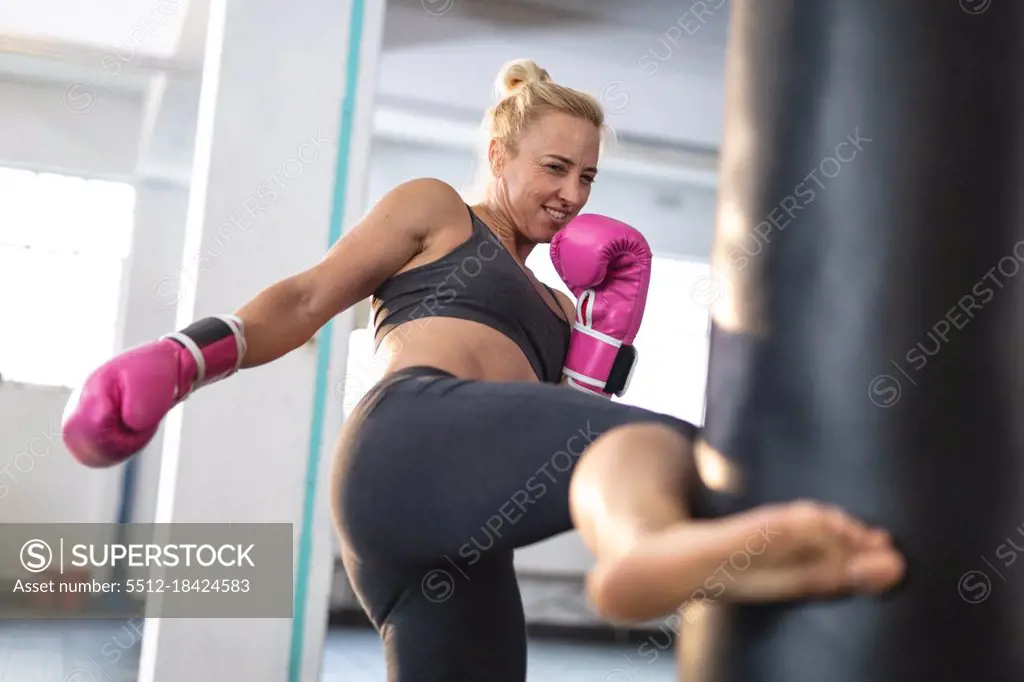 Strong caucasian woman exercising at gym, boxing using punching bag. strength and fitness cross training for boxing.