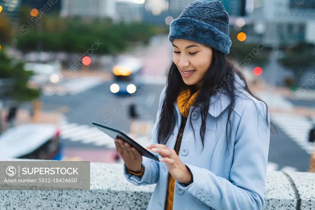 Asian woman using tablet and smiling in the street. independent young woman out and about in the city.