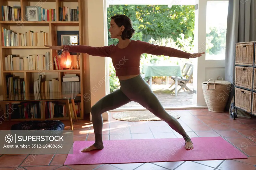 Caucasian woman in living room, practicing yoga, stretching. domestic lifestyle, enjoying leisure time at home.